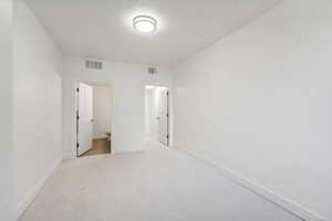 Unfurnished bedroom with baseboards, light carpet, and connected bathroom