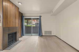 Unfurnished living room featuring light wood-type flooring, a fireplace, and baseboards