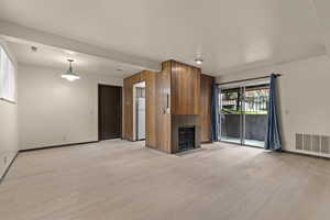 Unfurnished living room with baseboards, light wood-type flooring, and a tiled fireplace