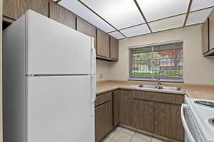 Kitchen with white appliances, a sink, light countertops, and light tile patterned floors