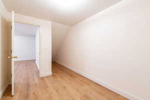 Bonus room featuring light wood-style flooring, baseboards, and lofted ceiling