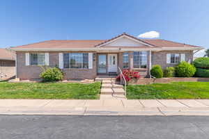 Ranch-style house featuring a tile roof, brick siding, and a front lawn