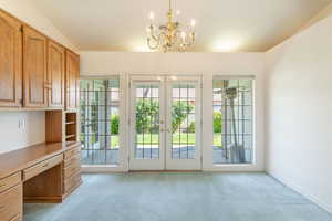 Entryway with light carpet, a chandelier, french doors, and an office area