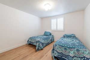 Bedroom with wood finished floors, baseboards, and a textured ceiling