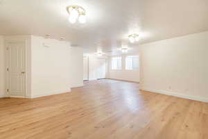 Unfurnished room with light wood finished floors, a textured ceiling, and baseboards