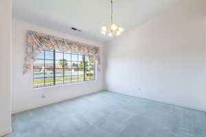 Empty room featuring a chandelier, baseboards, and carpet floors