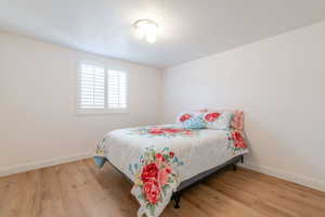 Bedroom with wood finished floors, baseboards, and a textured ceiling