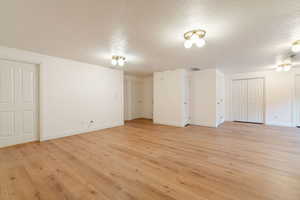 Spare room featuring a textured ceiling, light wood-style flooring, and baseboards