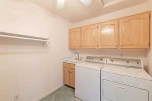 Laundry room featuring cabinet space, separate washer and dryer, baseboards, and light carpet