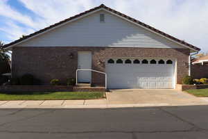 Ranch-style home with concrete driveway, brick siding, a tile roof, and an attached garage