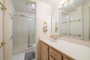 Full bathroom with toilet, a stall shower, tile patterned floors, and vanity