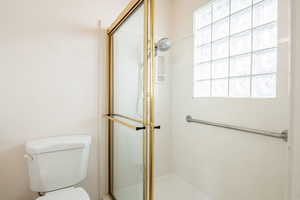 Full bathroom featuring a shower stall and toilet