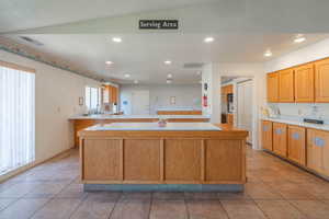 Kitchen featuring light countertops, light tile patterned flooring, recessed lighting, and a center island