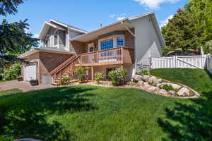 View of front facade featuring a garage, stairs, driveway, brick siding, and a gate