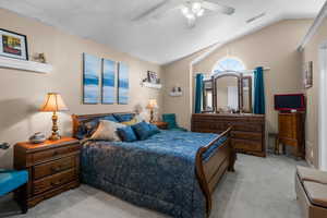 Bedroom featuring lofted ceiling, light carpet, ceiling fan, and a textured ceiling