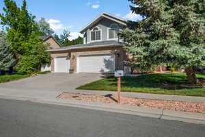 View of front of home featuring concrete driveway, a front yard, brick siding, and an attached garage