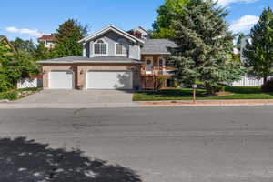 Split level home with concrete driveway, an attached garage, brick siding, and stairs