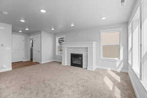 Unfurnished living room featuring carpet flooring, recessed lighting, a tiled fireplace, and baseboards