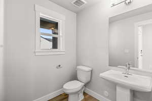 Bathroom with wood finished floors, baseboards, toilet, and a sink