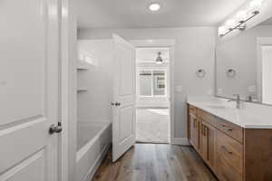 Full bathroom with vanity, wood finished floors, ceiling fan, a bathtub, and baseboards