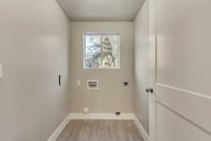 Laundry room featuring electric dryer hookup, hookup for a washing machine, light wood-type flooring, and baseboards