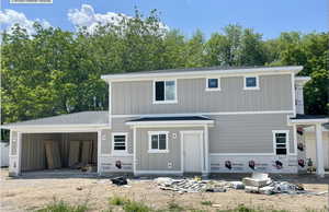 View of front facade with board and batten siding, a garage, driveway, and a shingled roof