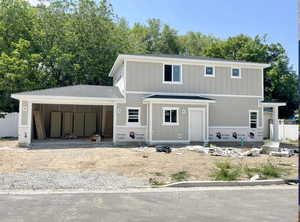 View of front of property featuring board and batten siding, a garage, driveway, and roof with shingles