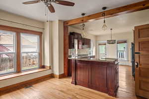 Kitchen featuring fridge, ceiling fan, light wood finished floors, baseboards, and hanging light fixtures