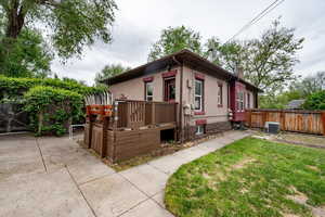 View of front of property featuring central air condition unit, a chimney, a wooden deck, and brick siding