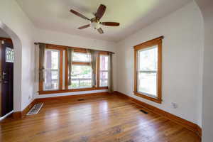 Unfurnished room featuring arched walkways, baseboards, wood finished floors, and ceiling fan