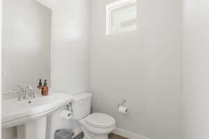 Half bath with toilet, a sink, and baseboards