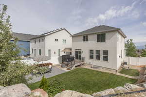 Back of property featuring stucco siding, a patio area, a wooden deck, and a gate
