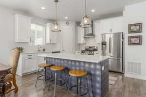 Kitchen featuring appliances with stainless steel finishes, a sink, wood finished floors, light countertops, and recessed lighting