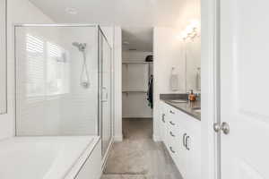 Bathroom with a shower stall, a garden tub, double vanity, and a spacious closet