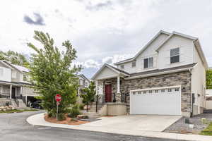 View of front of house featuring a garage, driveway, stone siding, and board and batten siding