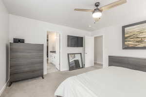 Bedroom with light colored carpet, baseboards, connected bathroom, and ceiling fan
