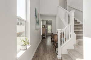 Entrance foyer with wood finished floors, a towering ceiling, stairs, and baseboards