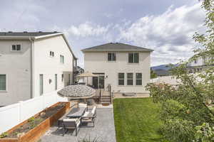 Back of house with a vegetable garden, stucco siding, and a patio area