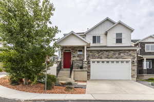 Craftsman-style house featuring board and batten siding, a garage, driveway, and stone siding