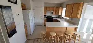 Main unit-Kitchen main unit with stainless steel range with electric cooktop, white refrigerator with ice dispenser, a sink, a peninsula, and under cabinet range hood