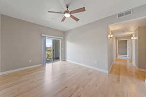 Empty room with a ceiling fan, light wood-style flooring, and baseboards