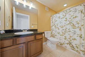 Bathroom featuring tile patterned floors, toilet, vanity, baseboards, and a shower with shower curtain