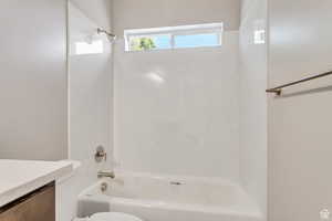 Bathroom featuring toilet, shower / bath combination, and vanity