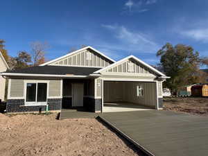 View of front facade with concrete driveway, board and batten siding, a garage, a porch, and roof with shingles