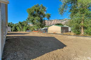 View of yard with a pole building, a mountain view, and an outdoor structure