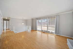 Unfurnished room with crown molding, light wood-style floors, and baseboards