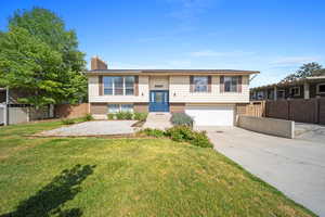 Split foyer home with a chimney, brick siding, concrete driveway, and a garage