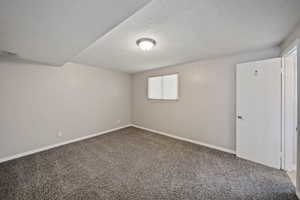 Spare room featuring carpet, a textured ceiling, and baseboards