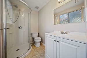 Bathroom featuring a shower stall, toilet, tile patterned flooring, and vanity