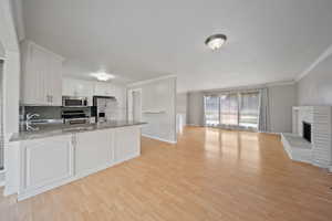 Kitchen with appliances with stainless steel finishes, open floor plan, a sink, a peninsula, and crown molding